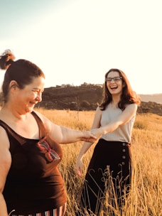 Women sitting together on a grassy hill, sharing stories and enjoying a peaceful moment in nature.