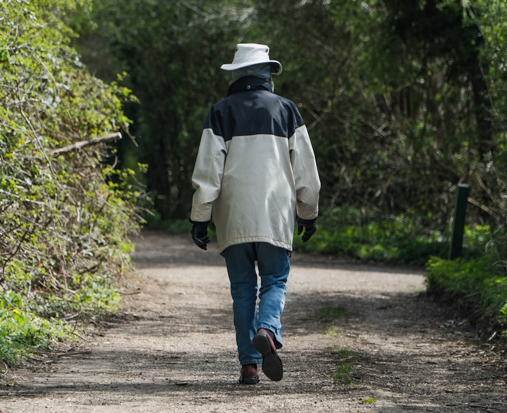 person in white jacket walking on dirt road during daytime