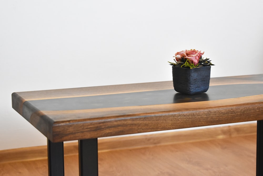 flor vermelha no vaso de cerâmica azul na mesa de madeira marrom