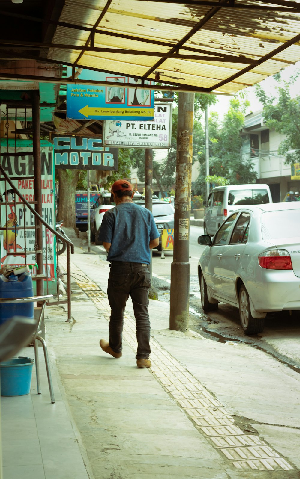 man in blue dress shirt and black pants standing beside white car during daytime