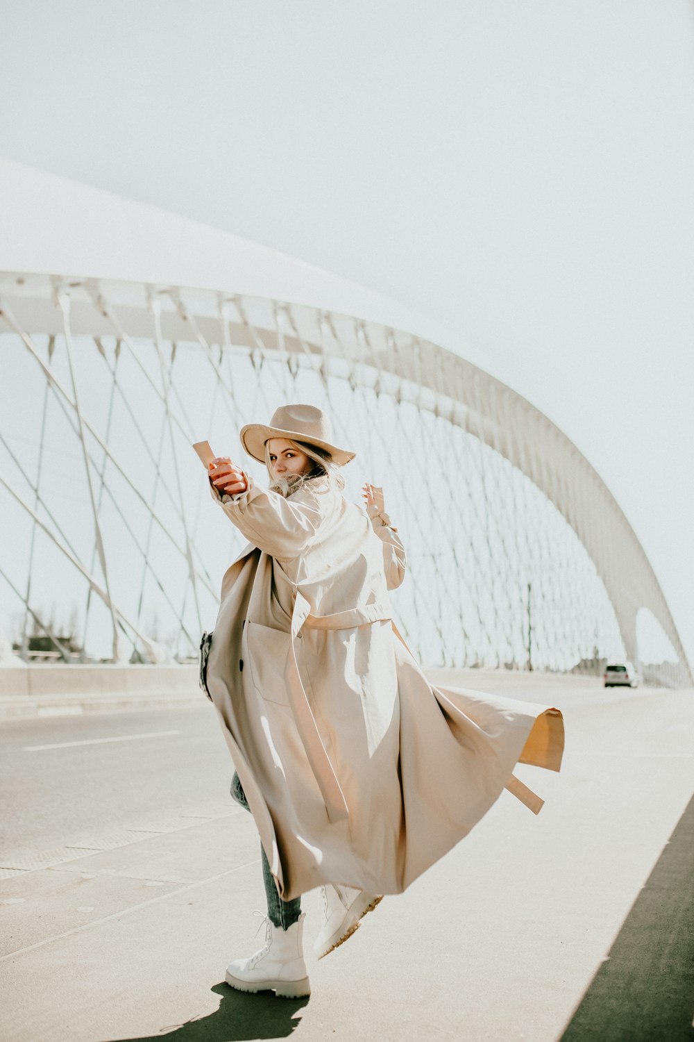 woman in brown coat and brown hat standing on white sand during daytime