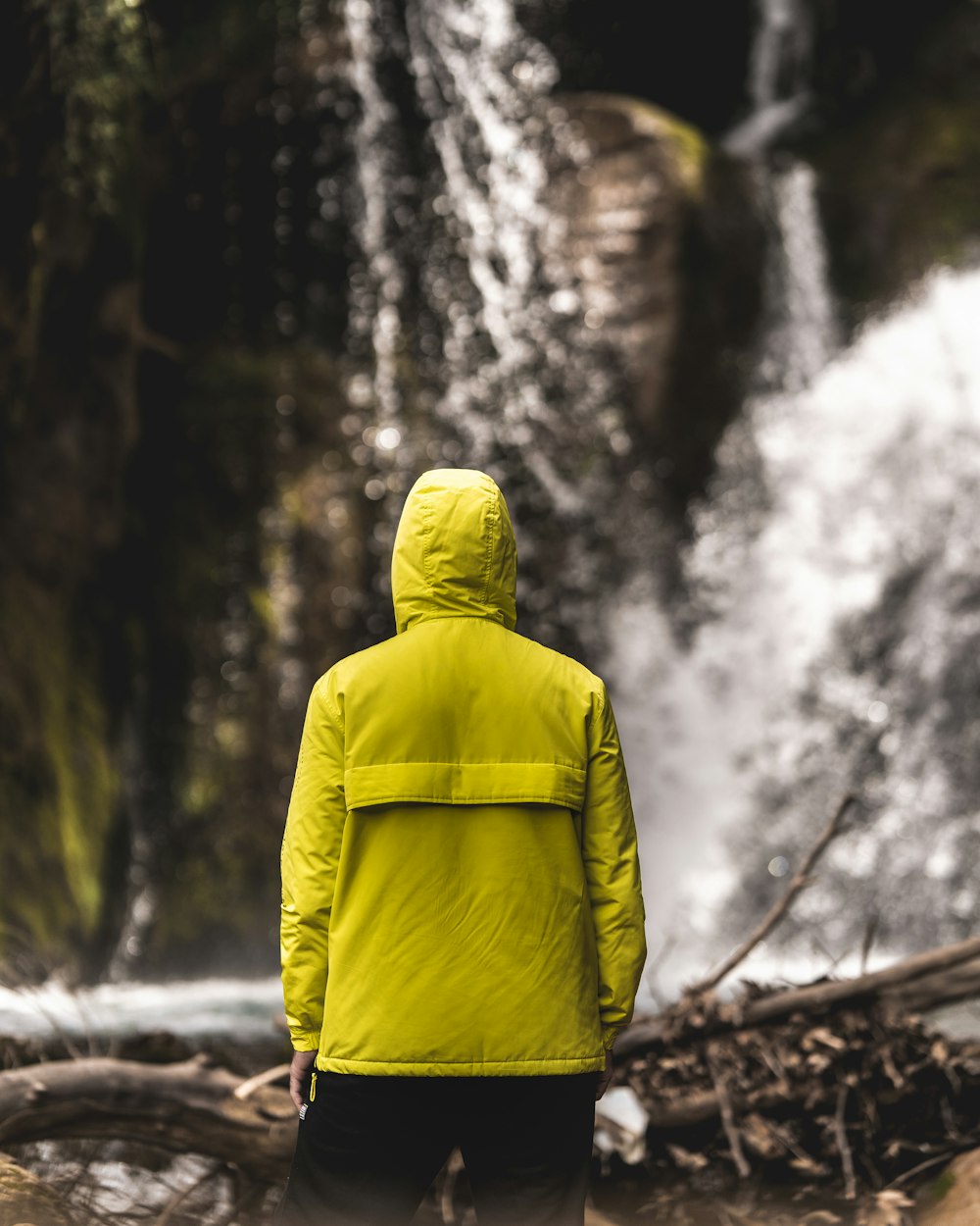 person in yellow hoodie standing near river