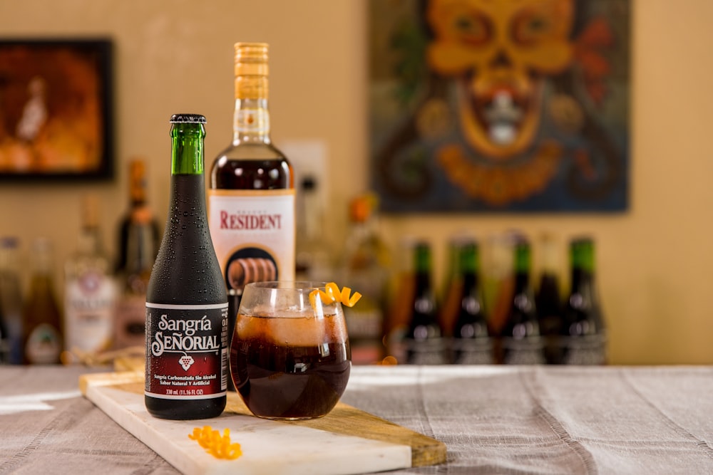 black glass bottle beside clear drinking glass