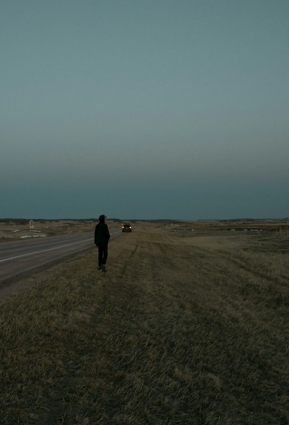 person in black jacket walking on brown field during daytime