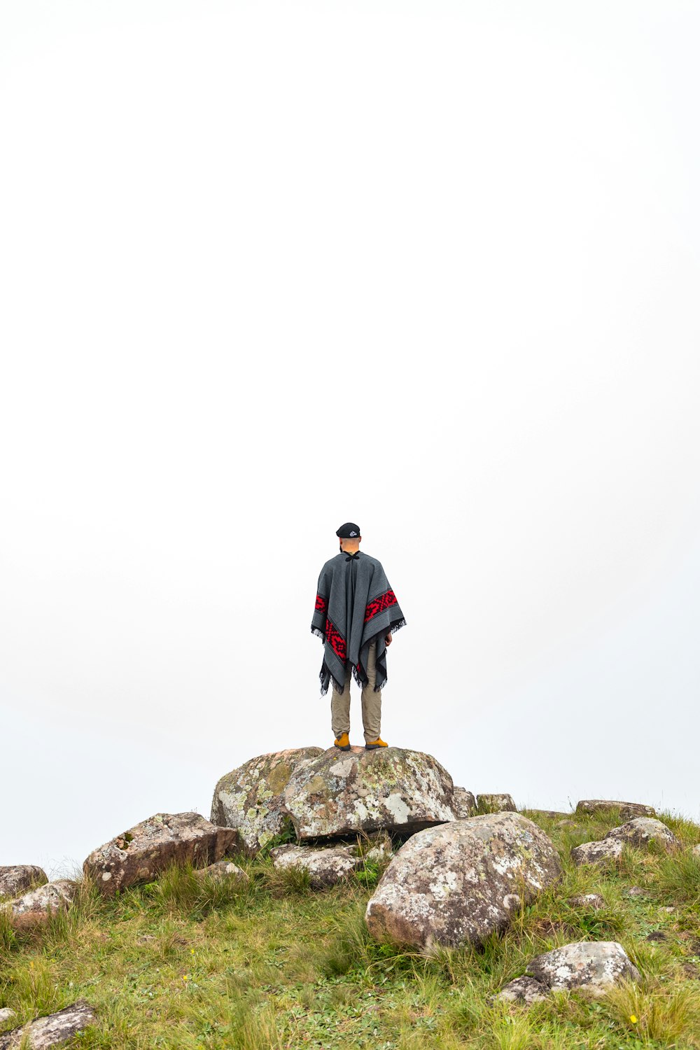 man in black jacket standing on rock