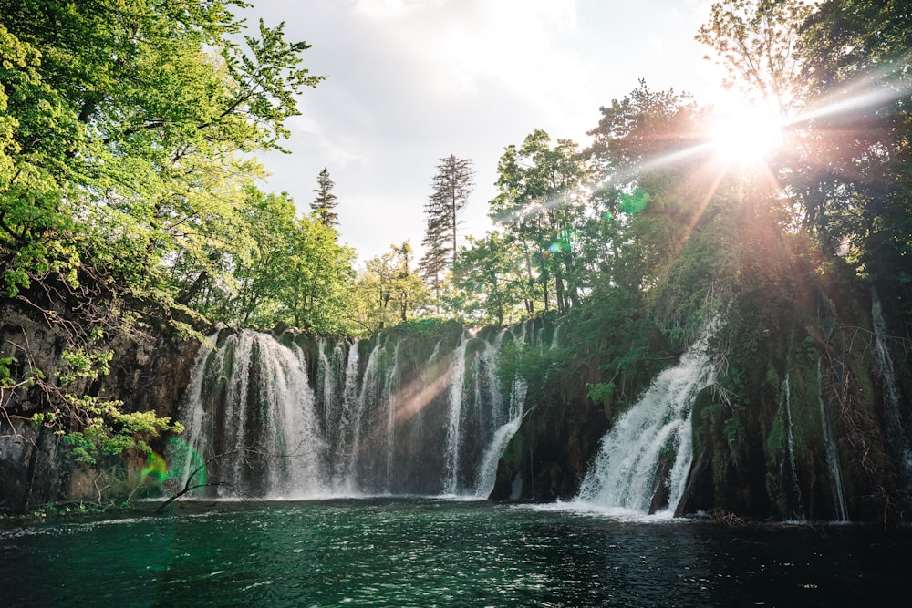 waterfalls in the middle of green trees during daytime