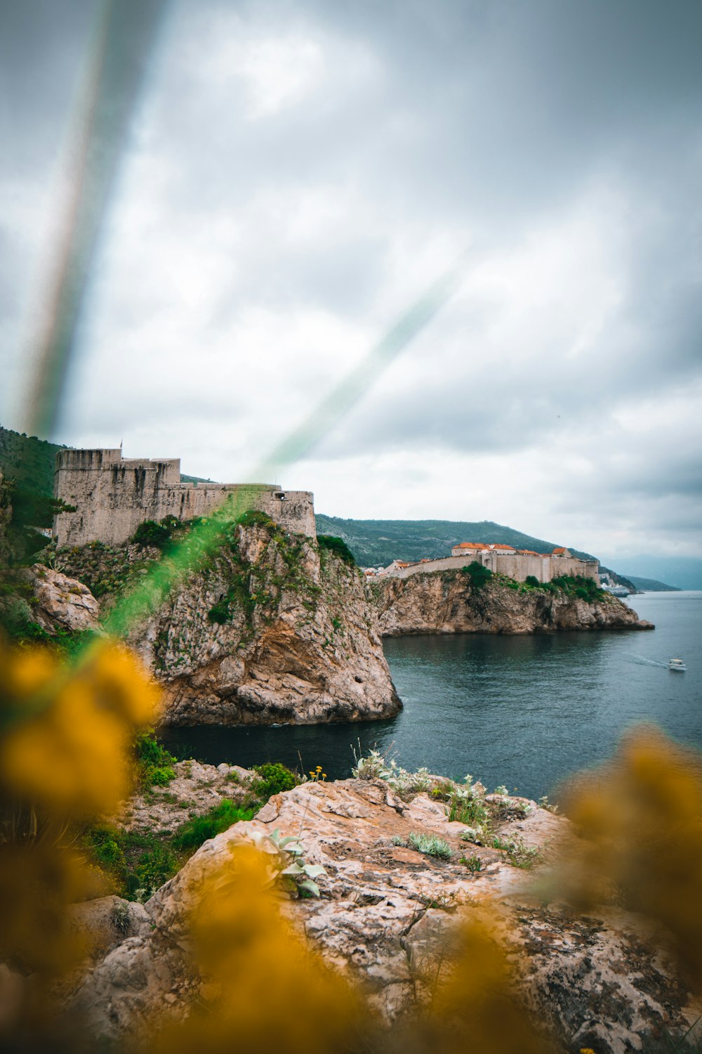 green mountain beside body of water under cloudy sky during daytime