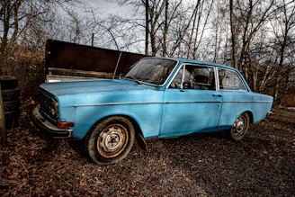 blue sedan parked near bare trees during daytime