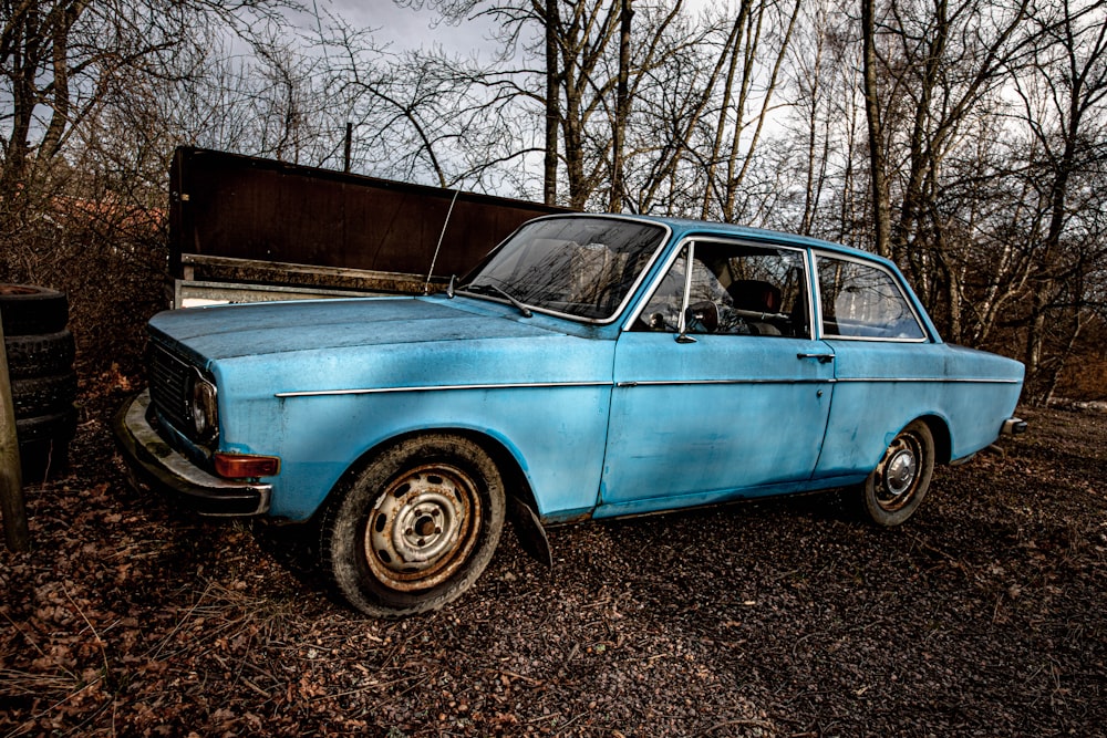 Blaue Limousine tagsüber in der Nähe von kahlen Bäumen geparkt