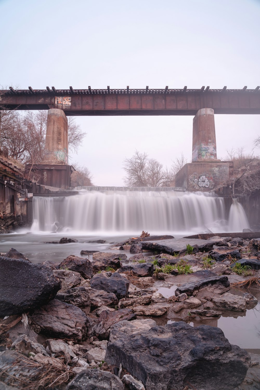 water falls under bridge during daytime