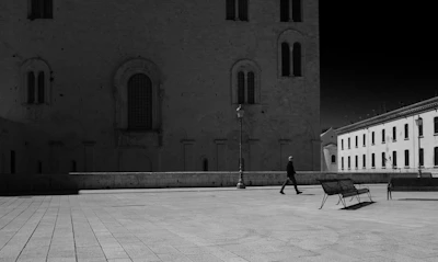 A quiet prison yard at dusk with a single figure walking alone along the fence.