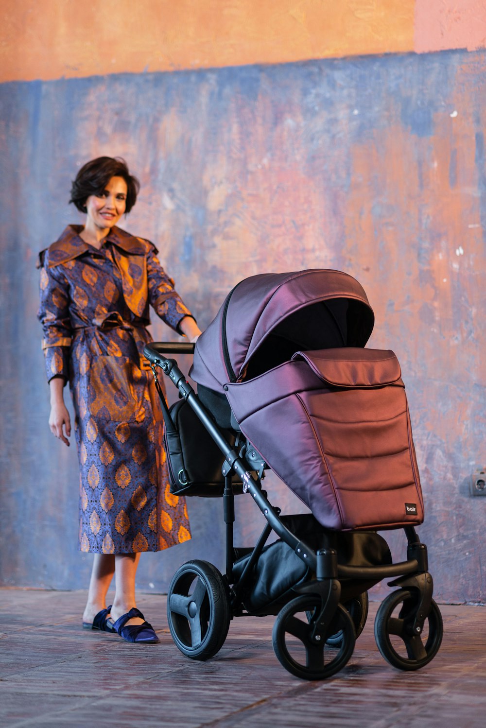 woman in brown and black floral dress standing beside black stroller