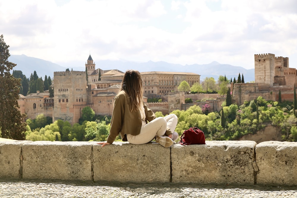 woman in beige long sleeve shirt sitting on gray concrete bench during daytime