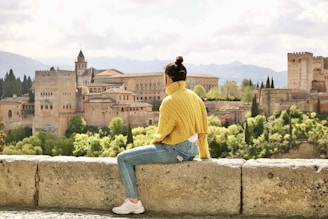 man in yellow long sleeve shirt and blue denim jeans sitting on concrete bench during daytime