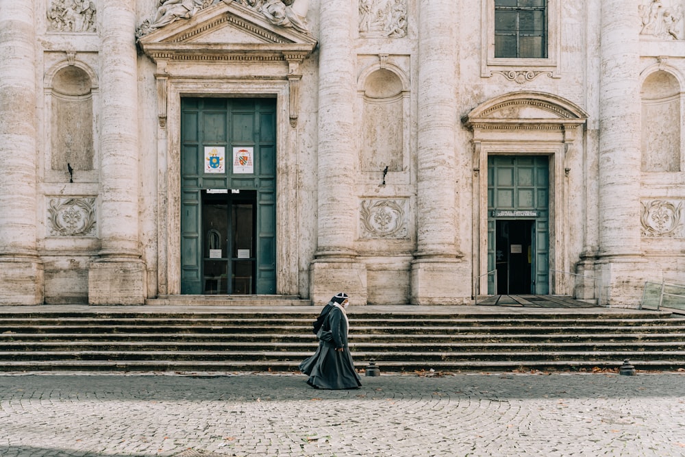 woman in black dress walking on sidewalk during daytime