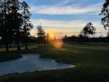 A beautiful sunset over a golf course, casting a golden glow on the landscape.