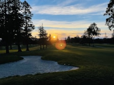 A beautiful sunset over a golf course, casting a golden glow on the landscape.