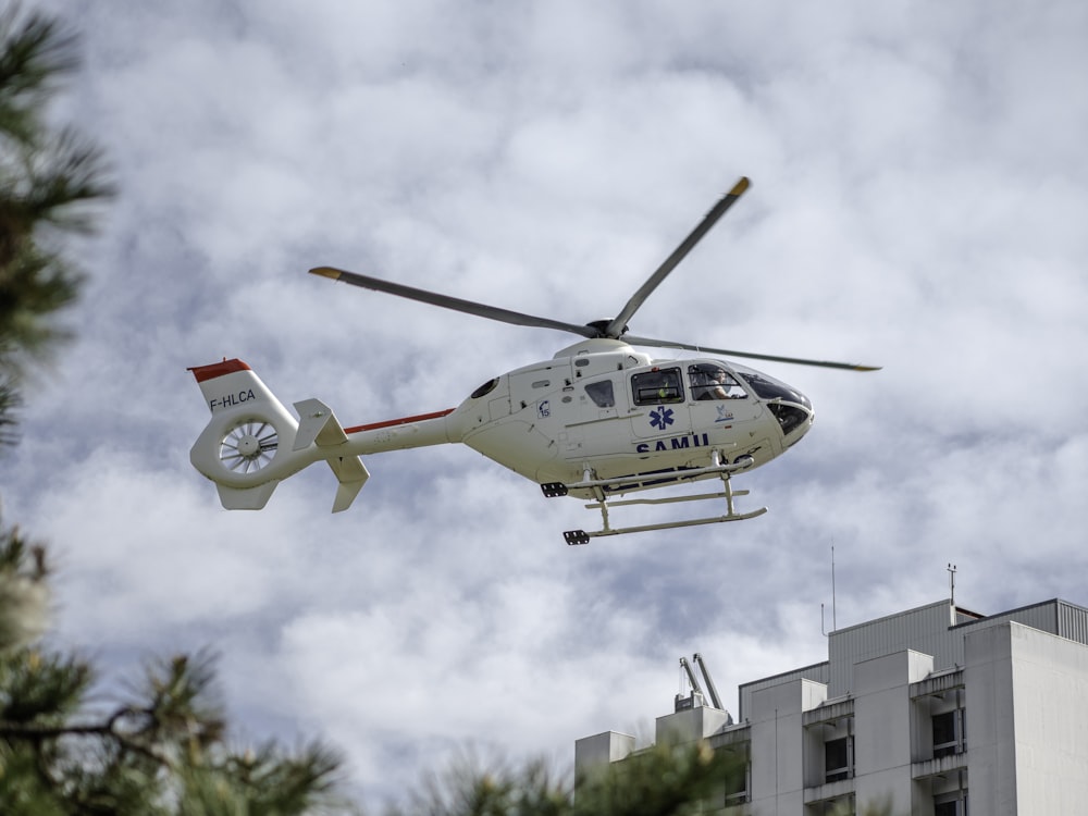 white and red helicopter flying in the sky during daytime