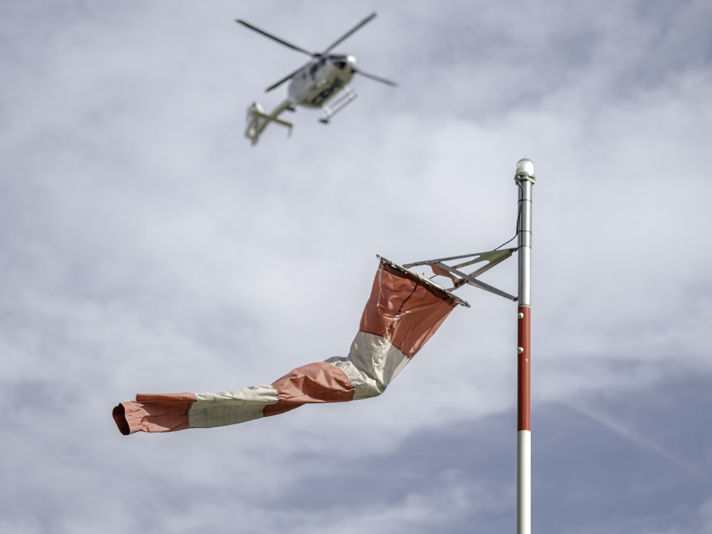 Bandera roja en poste blanco bajo cielo nublado durante el día