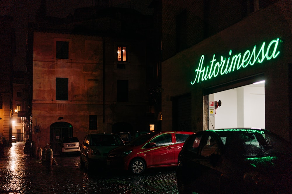 red sedan parked beside brown building during nighttime