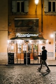 man in black jacket and black pants standing in front of brown wooden store during daytime