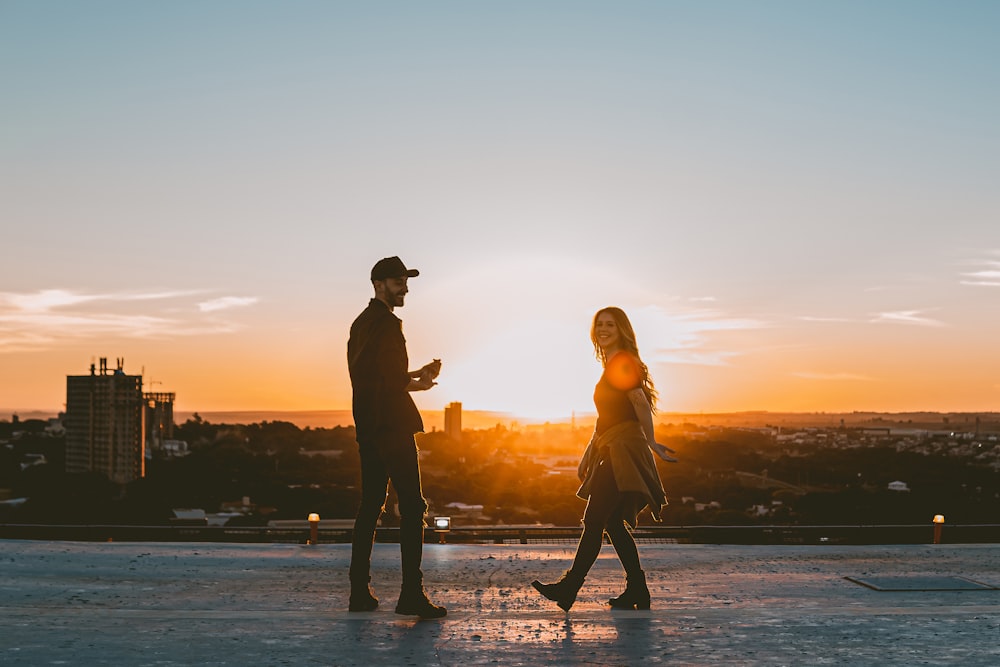 silhouette of man and woman standing on beach during sunset