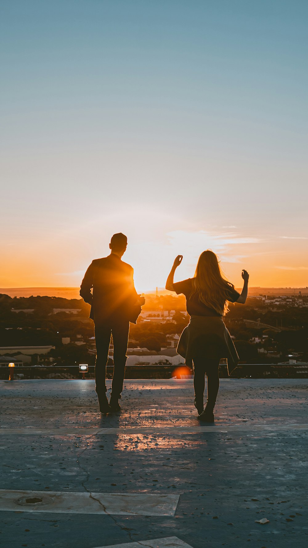 silhouette of man and woman standing on beach during sunset