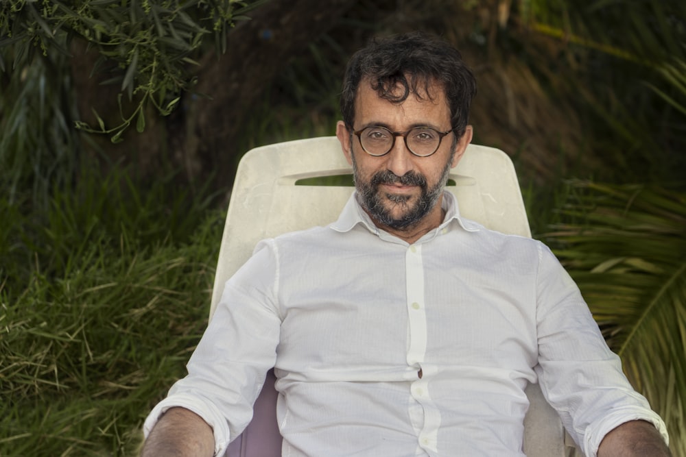 man in white dress shirt sitting on white chair