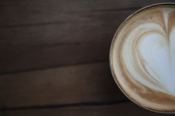 Close-up of a latte art heart on a creamy cappuccino in a rustic ceramic cup.
