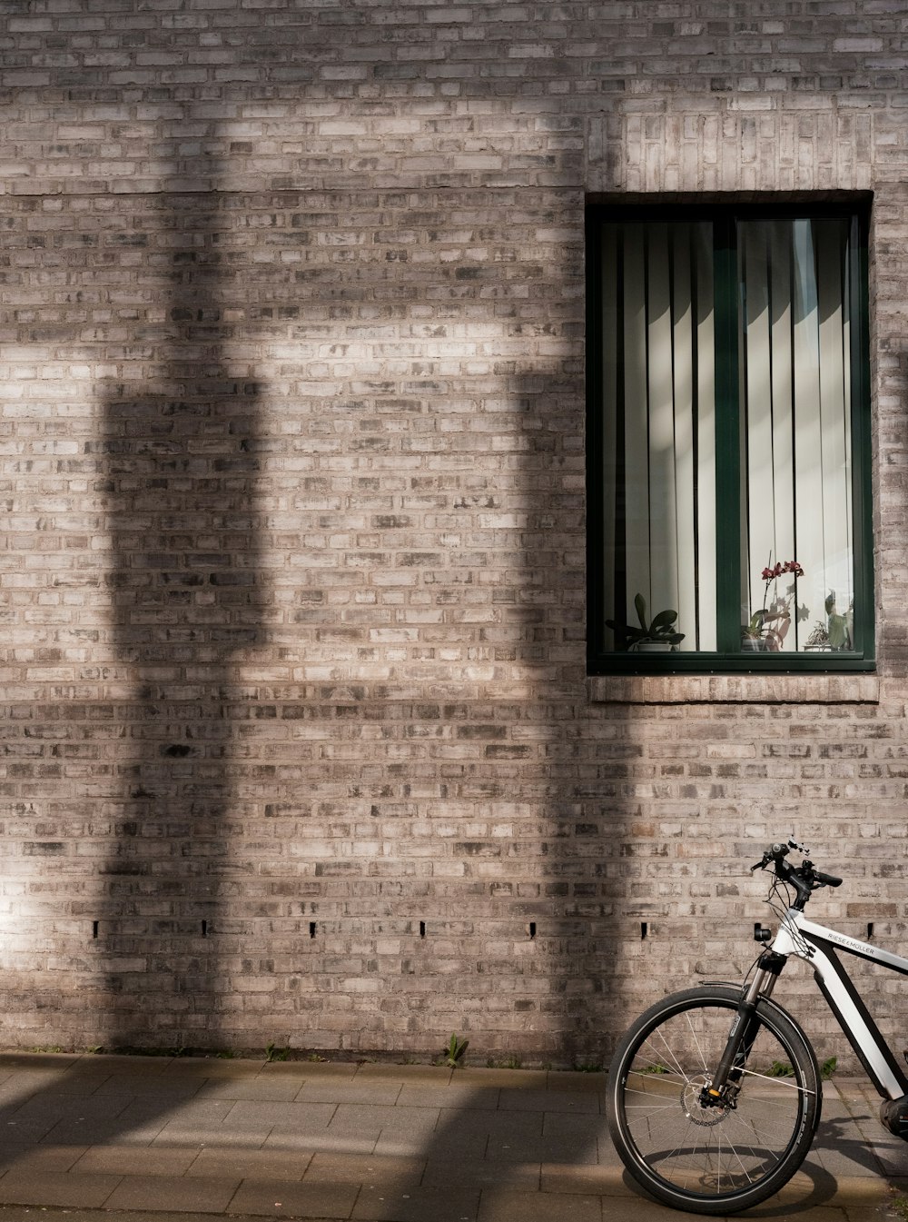 Bicicletta nera parcheggiata accanto al muro di mattoni marroni