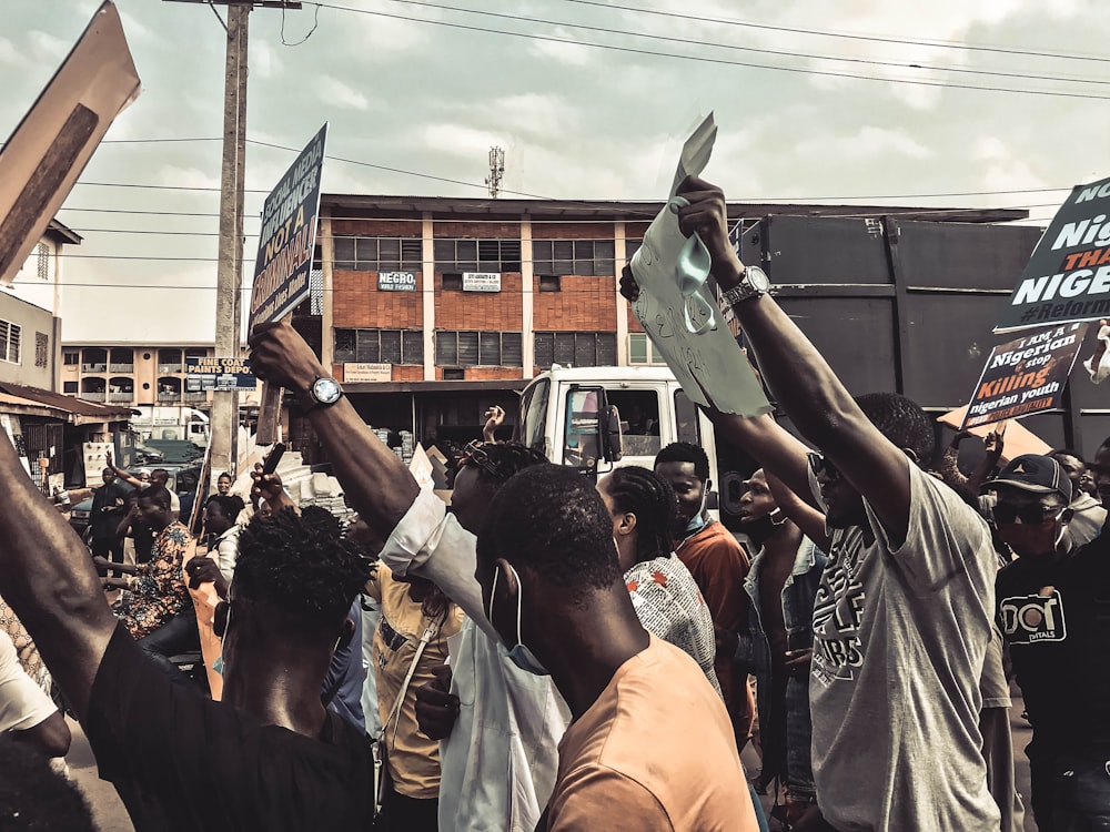 people standing and raising their hands during daytime