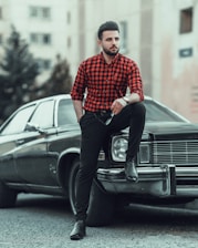 man in red and white checkered dress shirt and black pants standing beside black car during