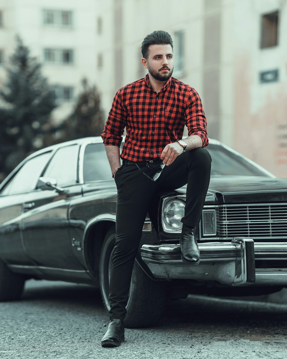 man in red and white checkered dress shirt and black pants standing beside black car during