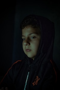Close-up of a sleek black hoodie with crimson red accents, draped over an urban concrete ledge at dusk.