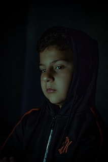 A moody shot of a black hoodie with a red metal band emblem illuminated by soft lighting.