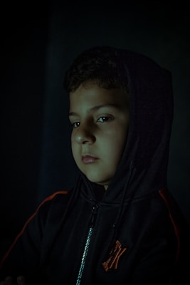 Close-up of a sleek black hoodie with crimson red accents, draped over an urban concrete ledge at dusk.