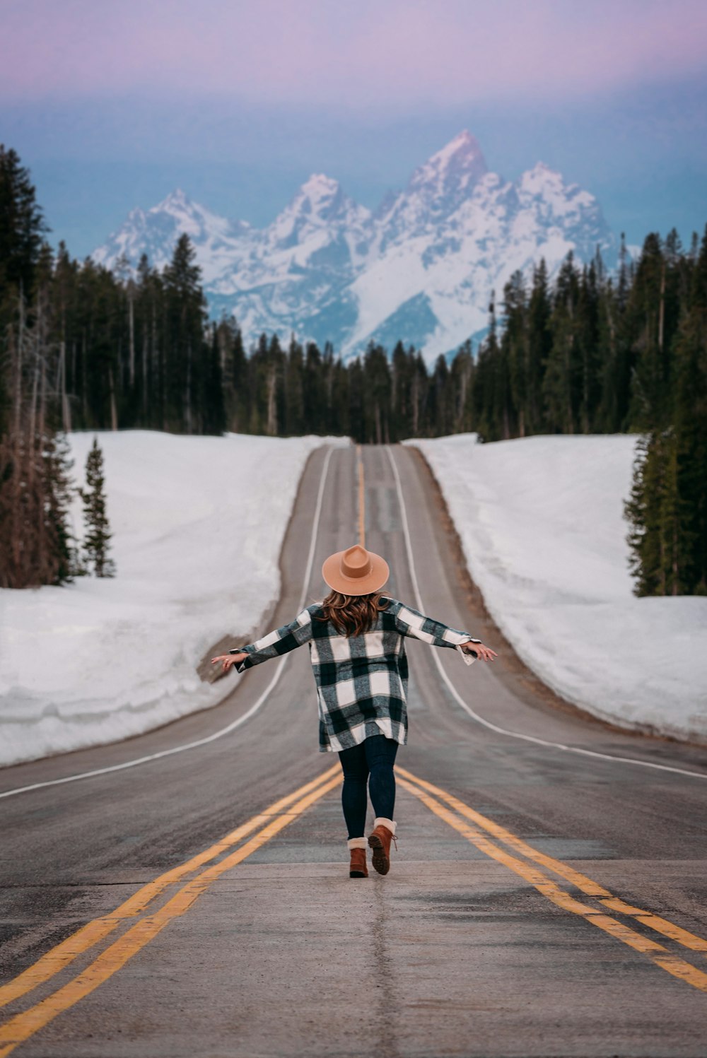 man in black and white plaid jacket and blue denim jeans walking on road during daytime