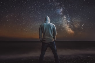 Black and white photo of a cozy hoodie with indigenous-inspired patterns under a starry night sky.