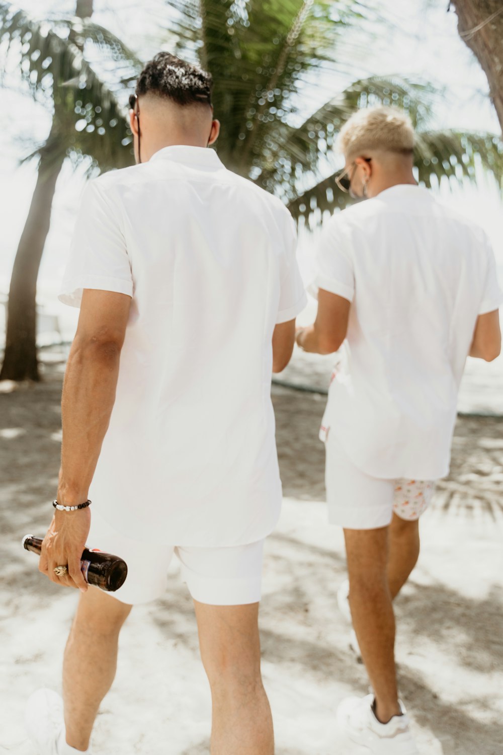 man in white crew neck t-shirt and white shorts holding black and brown leather bag