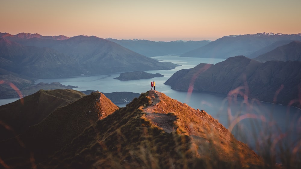 person standing on brown rock near lake during daytime