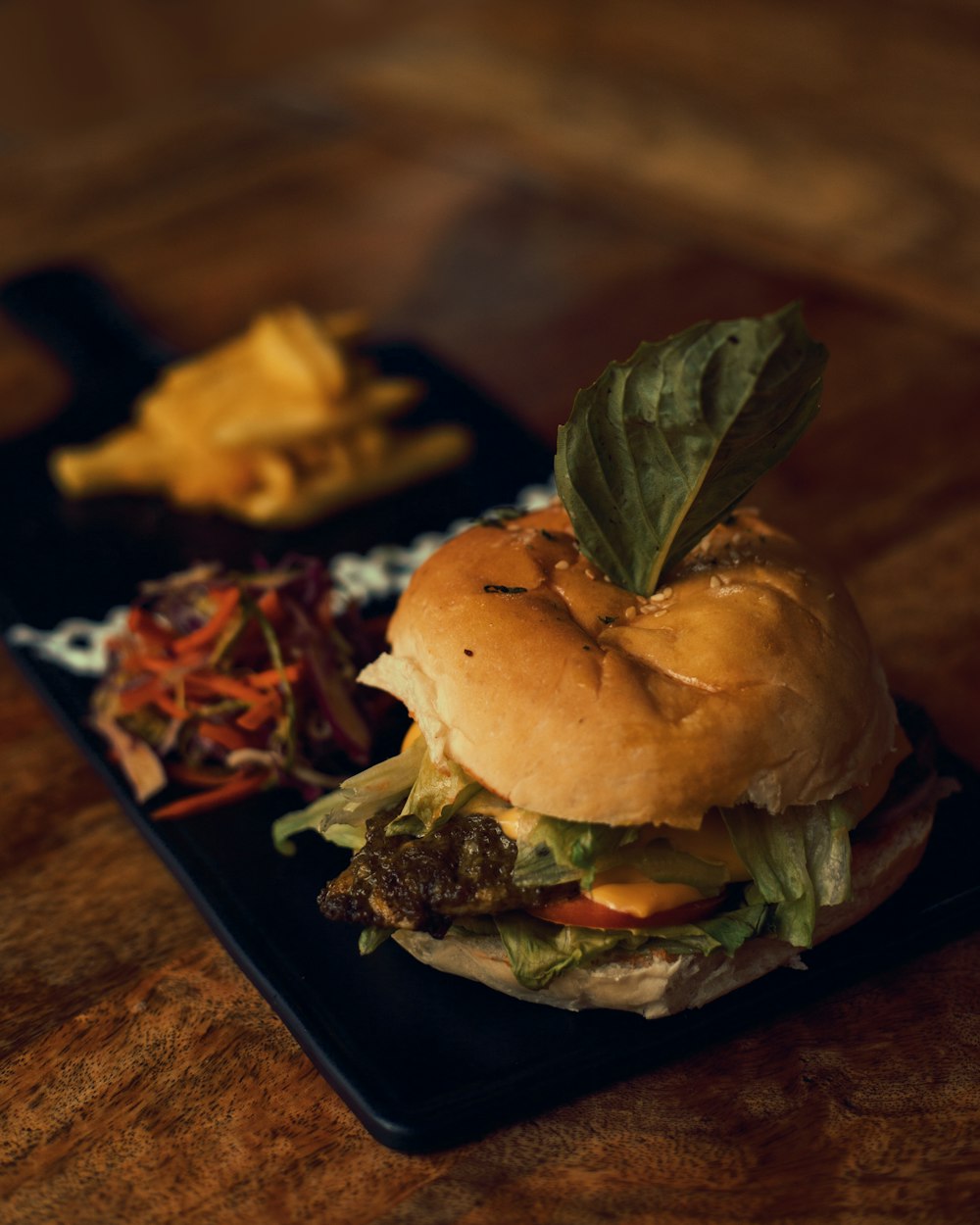 Burger mit Salat und Käse auf schwarzem Teller