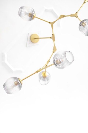 A modern, ceiling-mounted chandelier with a gold frame and multiple glass bulb covers. The design features articulated arms and clear glass coverings, creating an elegant and contemporary look against a white ceiling with decorative molding.