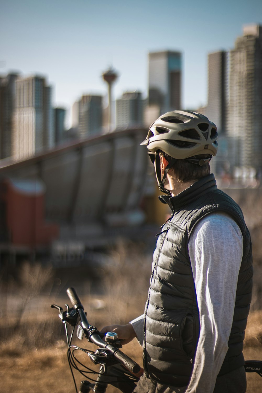 Homme en chemise noire et veste grise portant un casque blanc à vélo pendant la journée