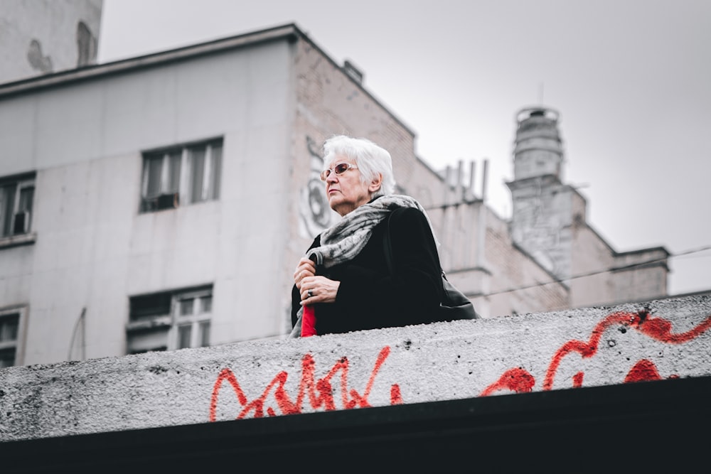 woman in black long sleeve shirt standing near white concrete building during daytime