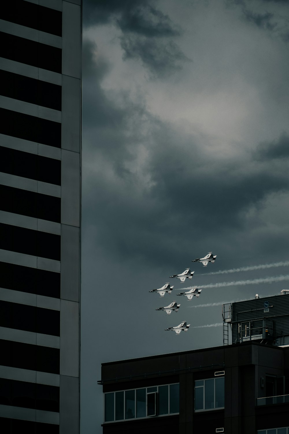 a group of fighter jets flying over a tall building