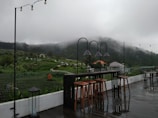 Outdoor seating area overlooking terraced fields and distant hills.