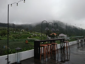 Outdoor seating area overlooking terraced fields and distant hills.