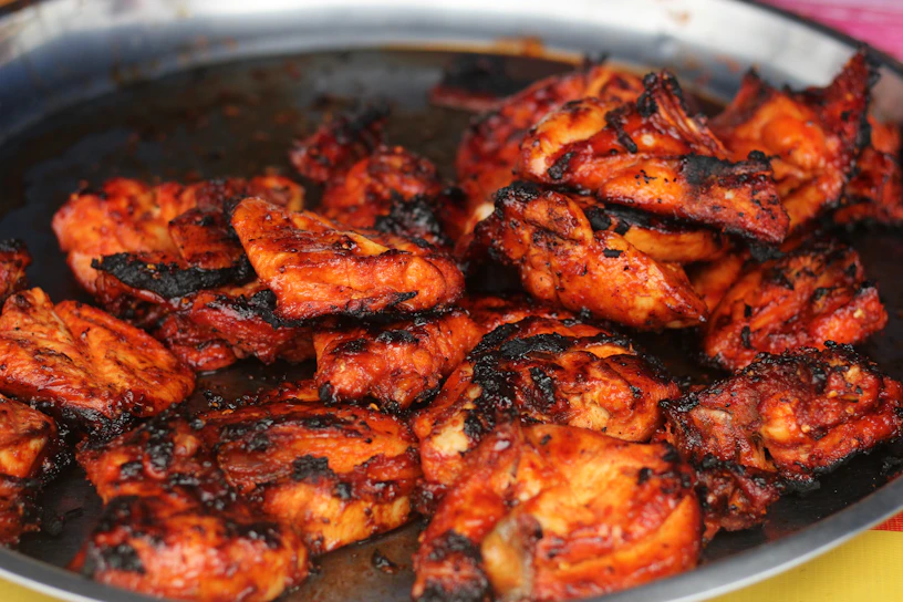 A vibrant plate of tandoori chicken with charred edges and fresh herbs.