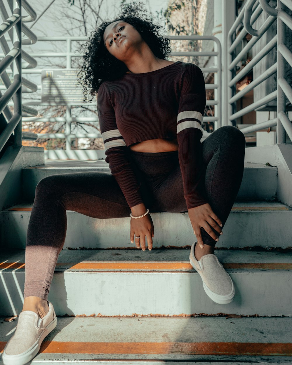 woman in red and white long sleeve shirt and black pants sitting on white concrete staircase