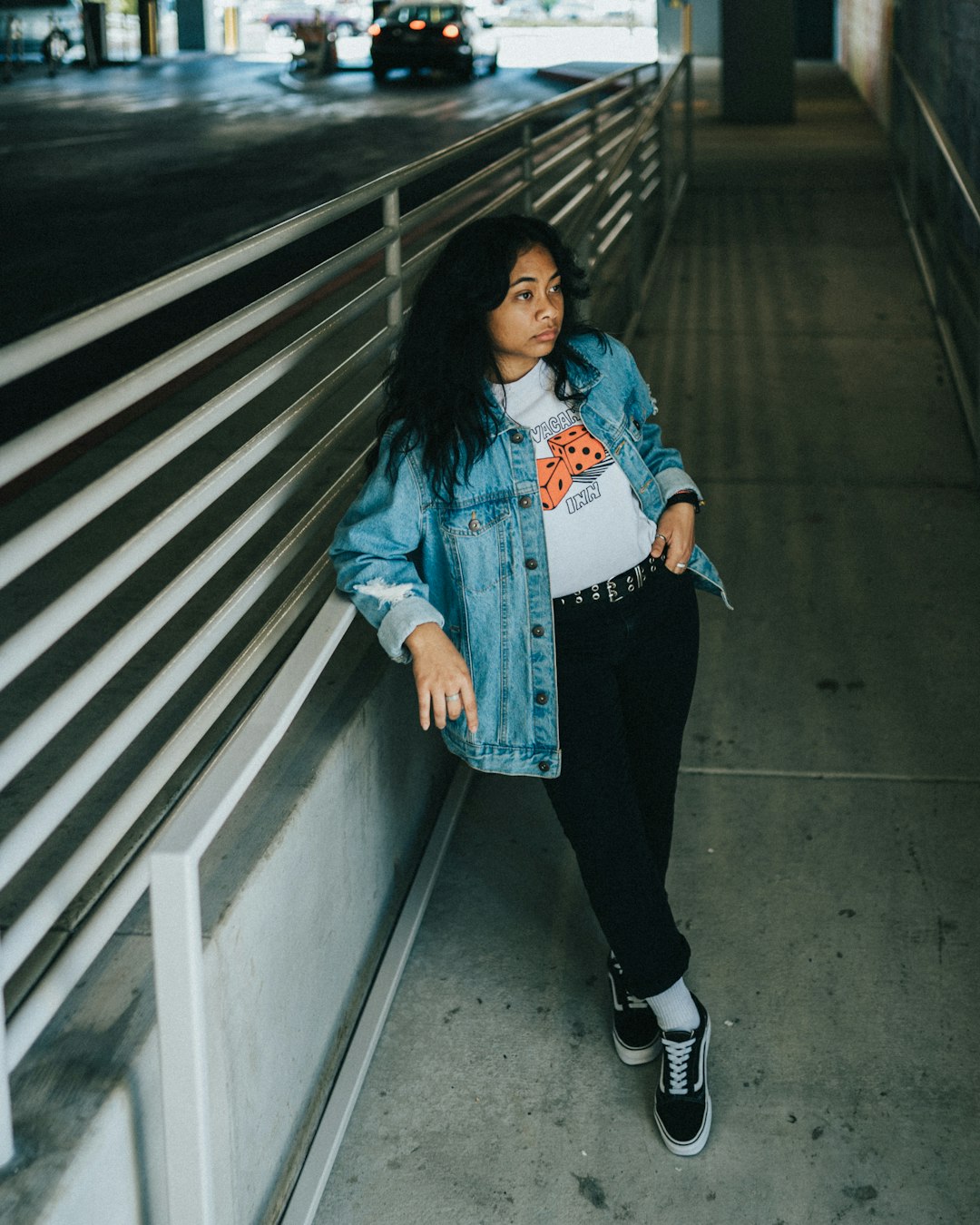 woman in blue denim jacket and black pants standing on gray concrete stairs